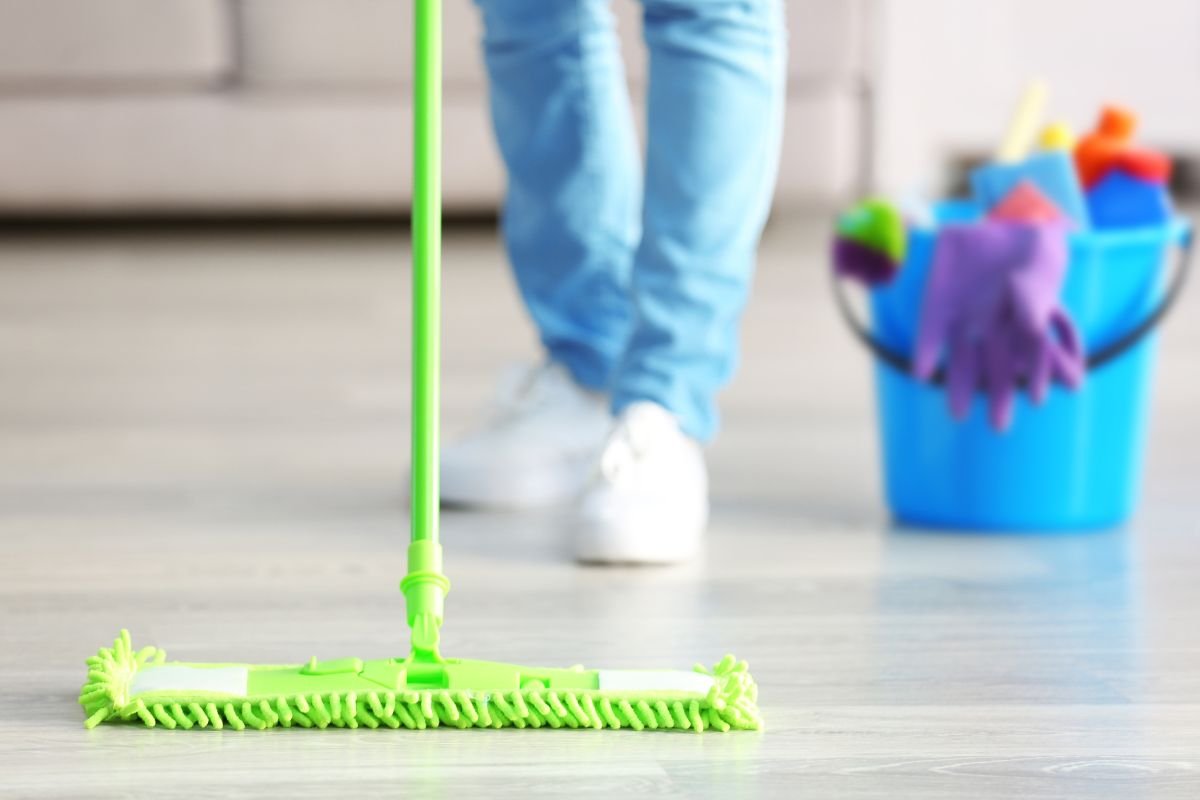 A person mops the floor, demonstrating effective cleaning techniques in a well-lit indoor space.