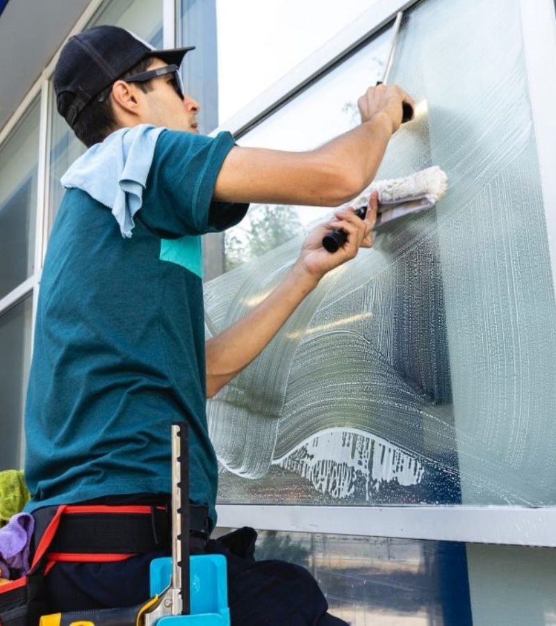 A professional man cleans a window, representing a commercial window cleaning service focused on quality and clarity.