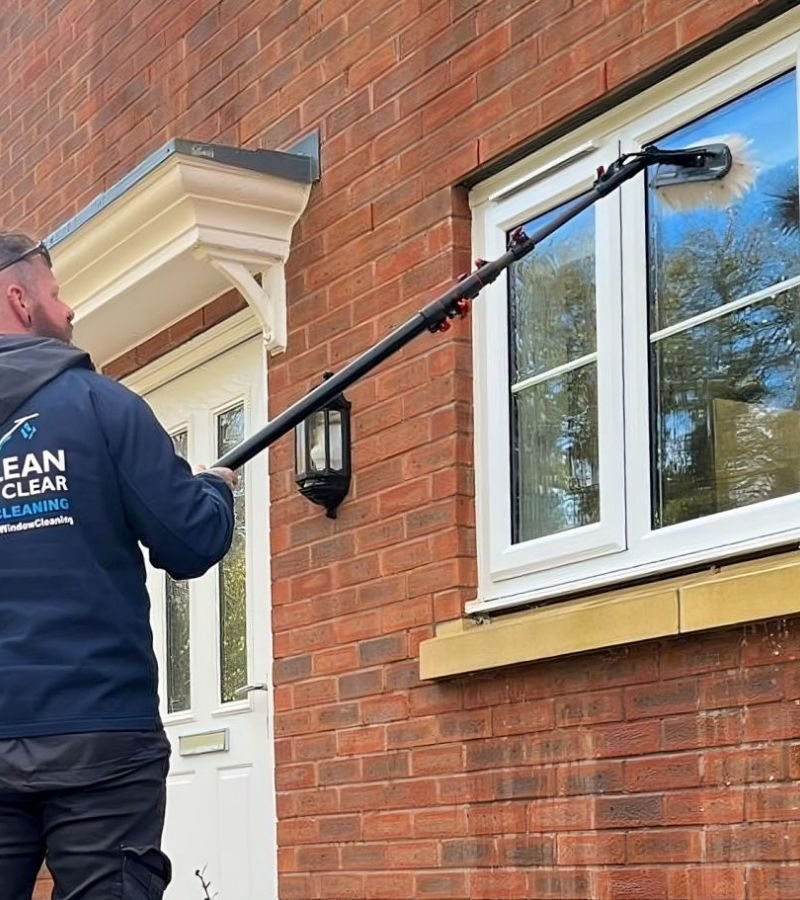 A man cleaning windows with a window cleaner, exemplifying the services offered by a domestic window cleaning company.